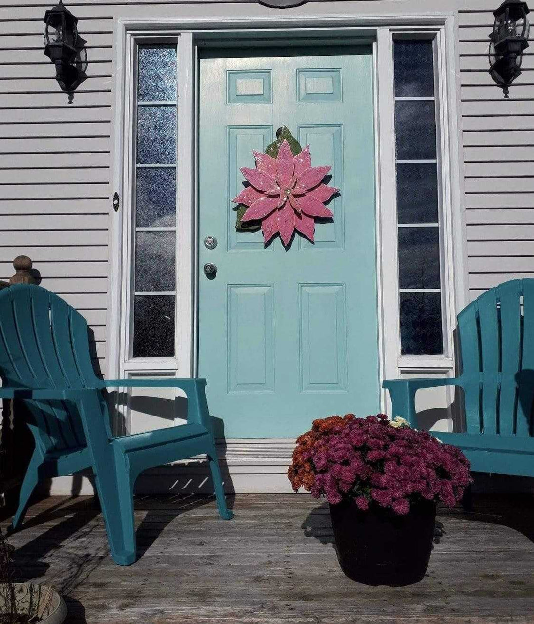Wooden Poinsettia flower decoration on teal front door, holiday season decor.