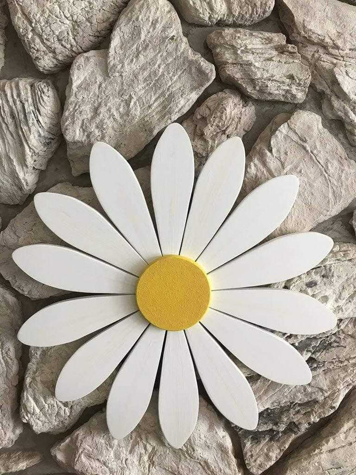 Hand-painted wooden art daisy on a stone background, symbolizing new beginnings and motherhood.