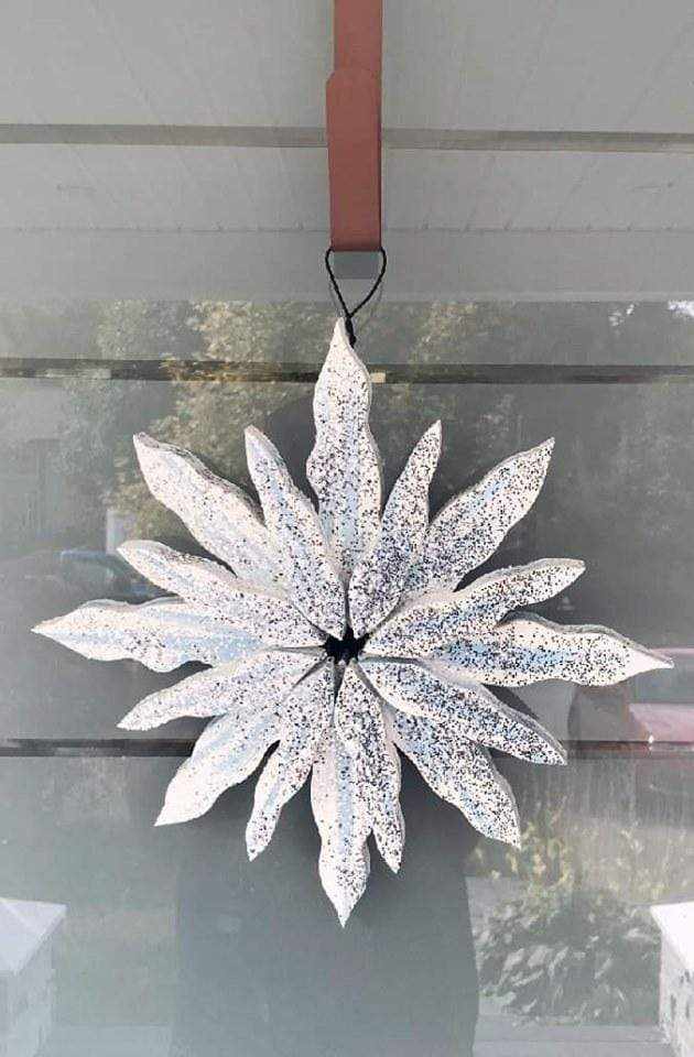 Handcrafted snowflake decoration with silver glitter, pine construction, and galvanized wire hanger.