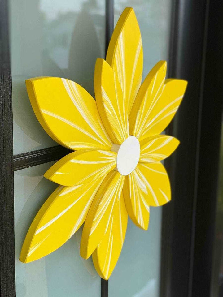 Bright yellow wooden flower decoration on a black-framed surface.