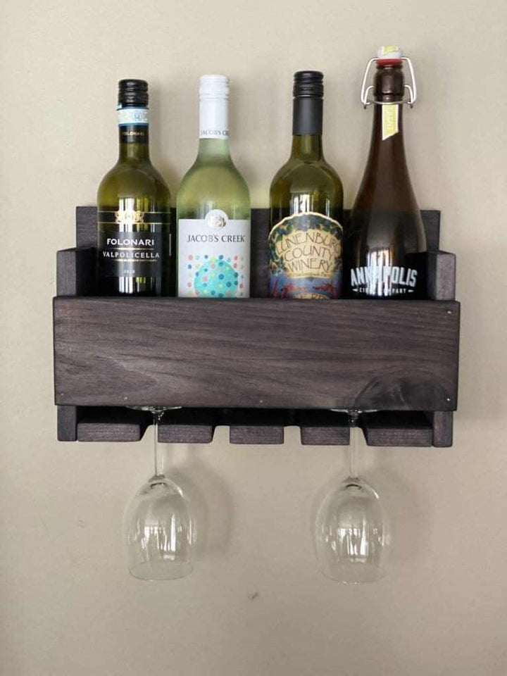 Rustic wall-mounted wine bottle and glass holder made of stained pine wood, holding four bottles and two glasses.