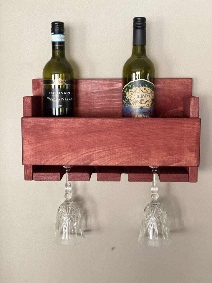 Rustic wall-mounted wine bottle and glass holder made from high-quality pine wood, holding two wine bottles and two glasses.