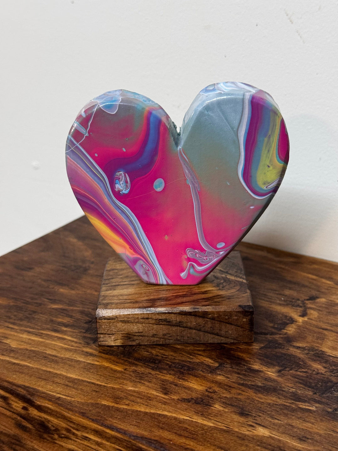 Colorful heart-shaped object on a wooden stand against a white background