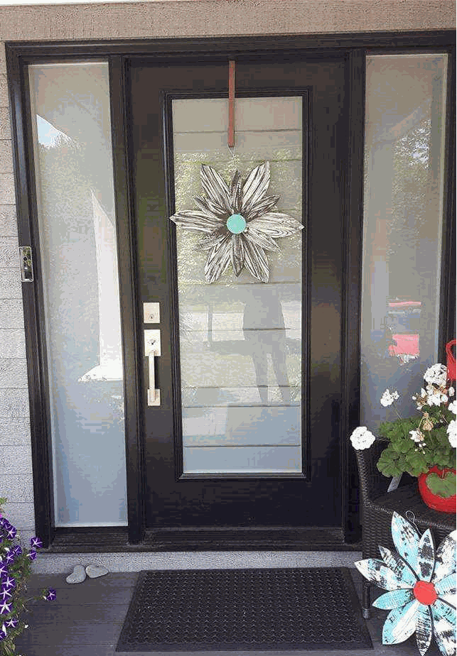 Handcrafted zebra-themed wooden flower decoration hanging on black door.