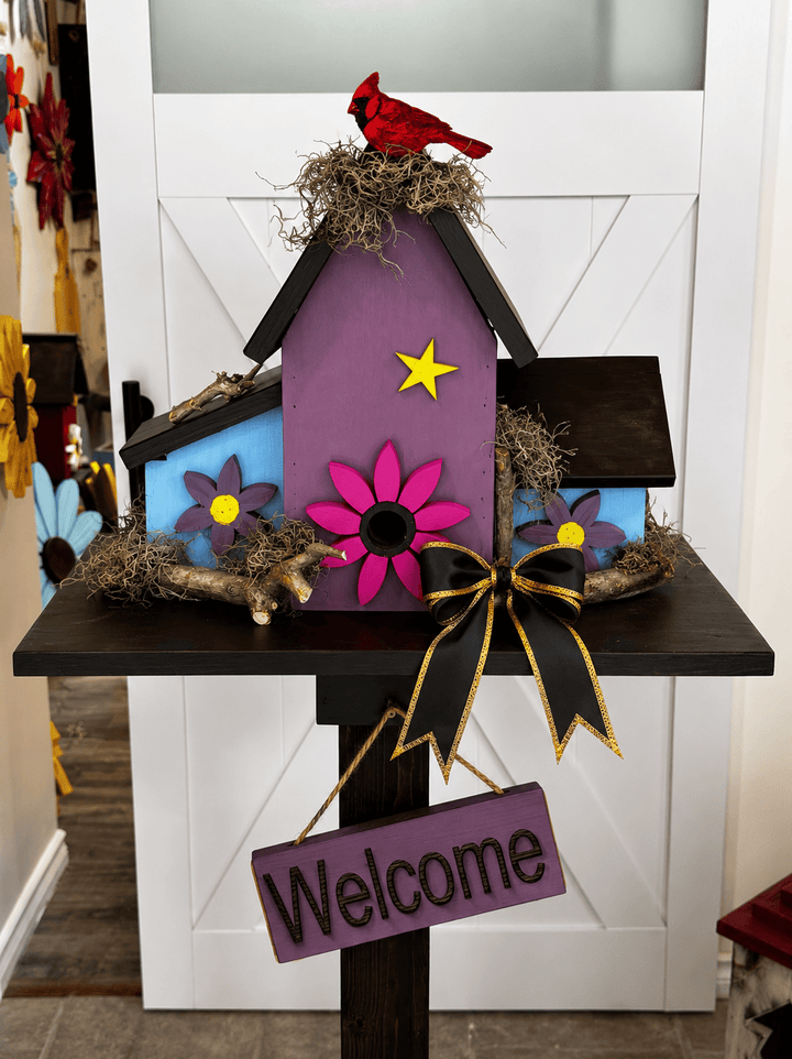 Decorative birdhouse with a red cardinal, flowers, and a &