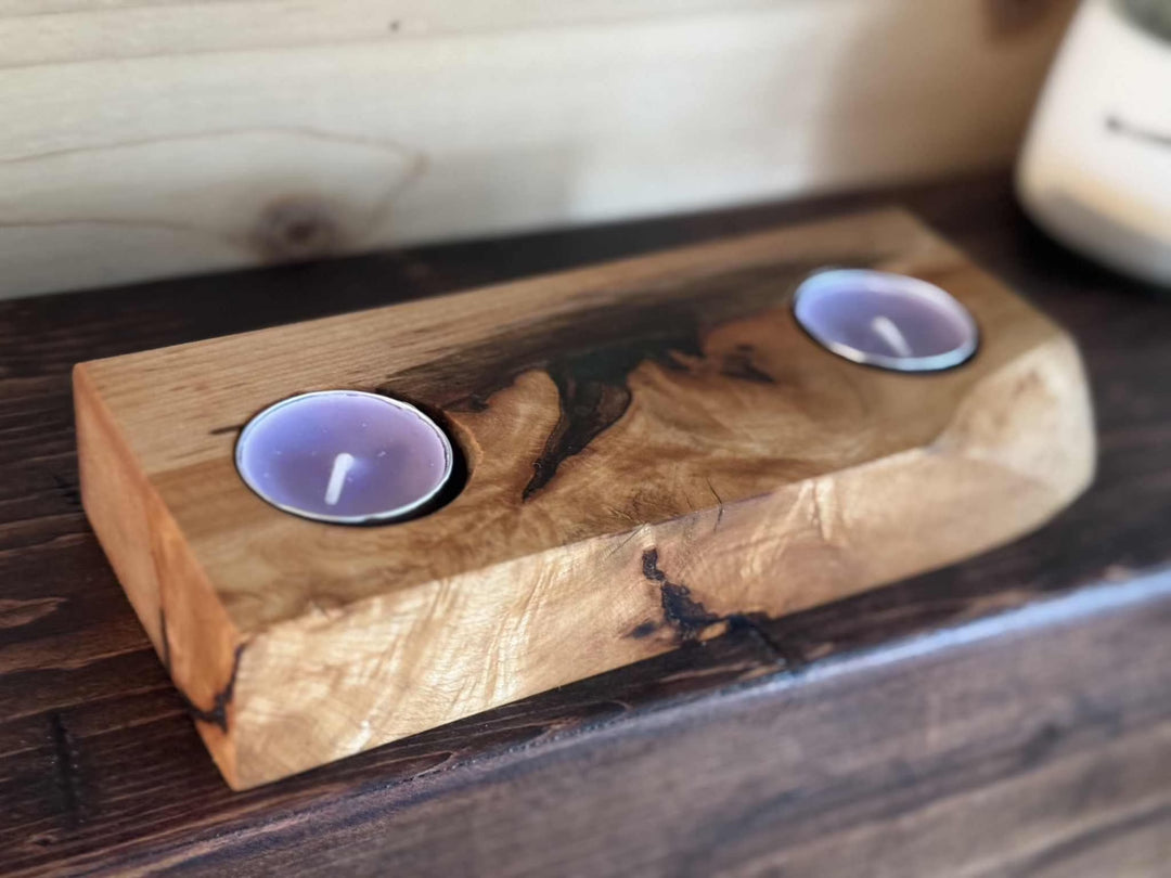 Handcrafted wooden tea light holder with two slots on a wooden surface.