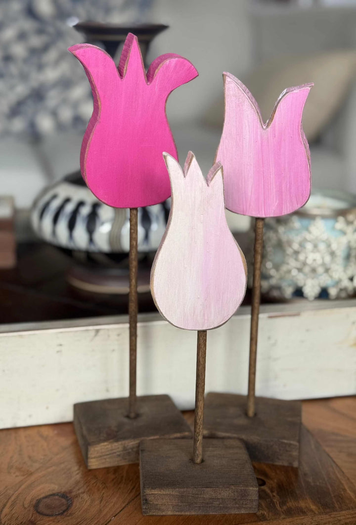 Handcrafted pink wooden tulips in rustic style displayed on a wooden table.