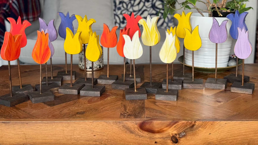 Handcrafted wooden tulips in vibrant colors displayed on a wooden table.