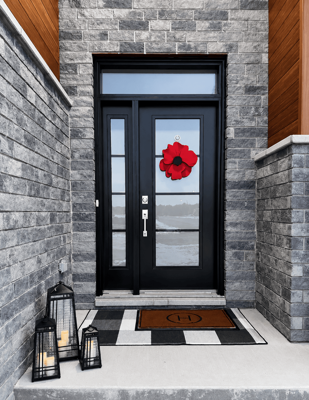 Black door with a red flower decoration on a stone building exterior.