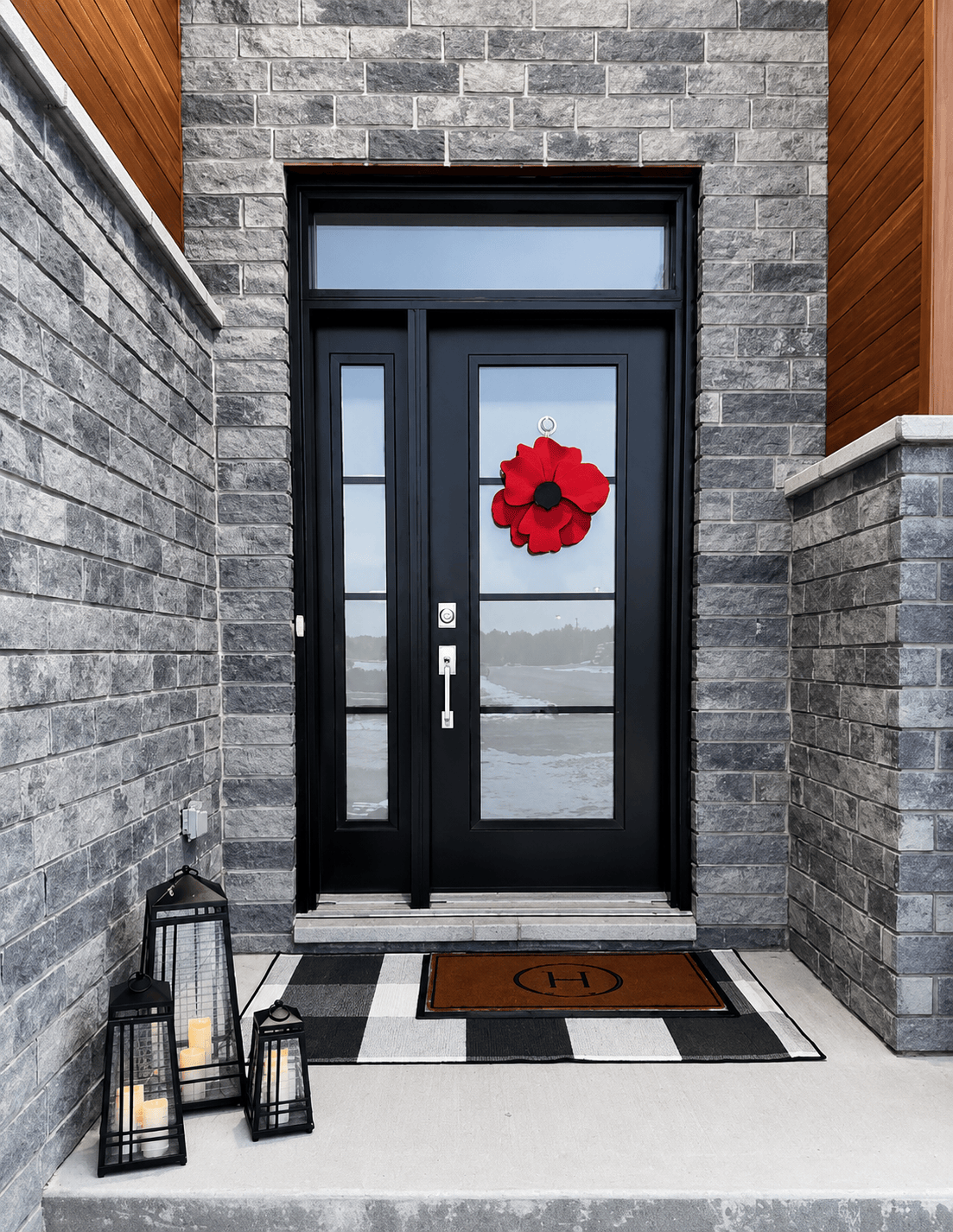 Black door with a red flower decoration on a stone building exterior.