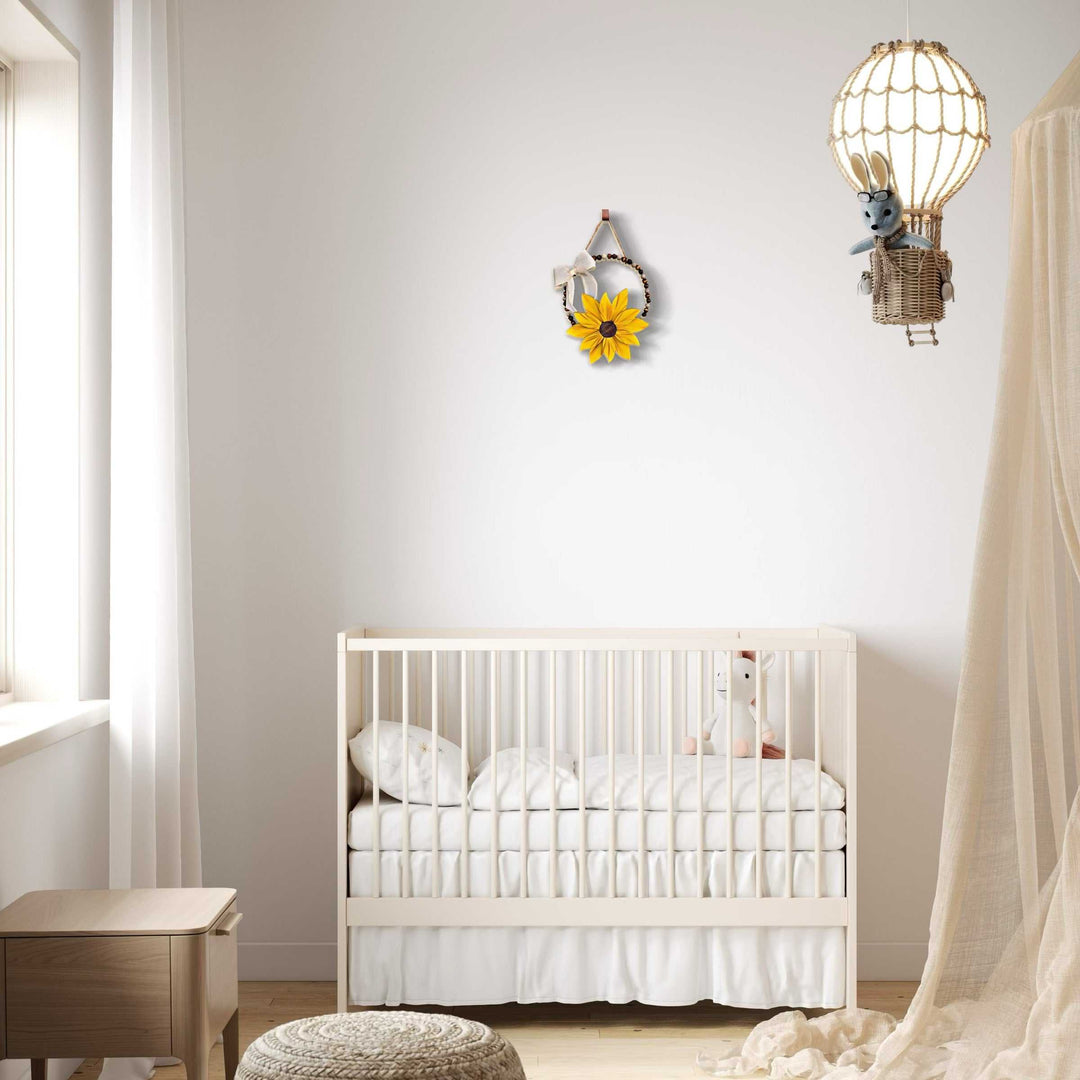 Boho style wooden bead wreath with hand-painted wooden flower hanging on a nursery wall.