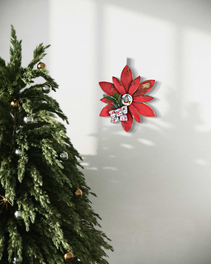 Festive hand-painted Christmas flower gnome outdoor décor against a wall, next to a decorated tree.