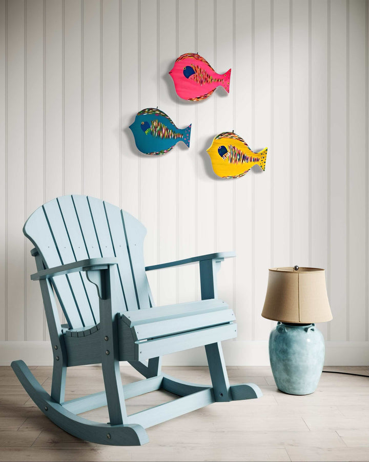 Hand painted folk art fish wall decor in vibrant colors, displayed on a white panel wall.