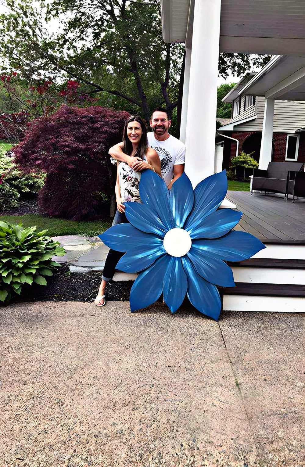 Large handcrafted wooden flower decoration in vivid blue, outdoor display.