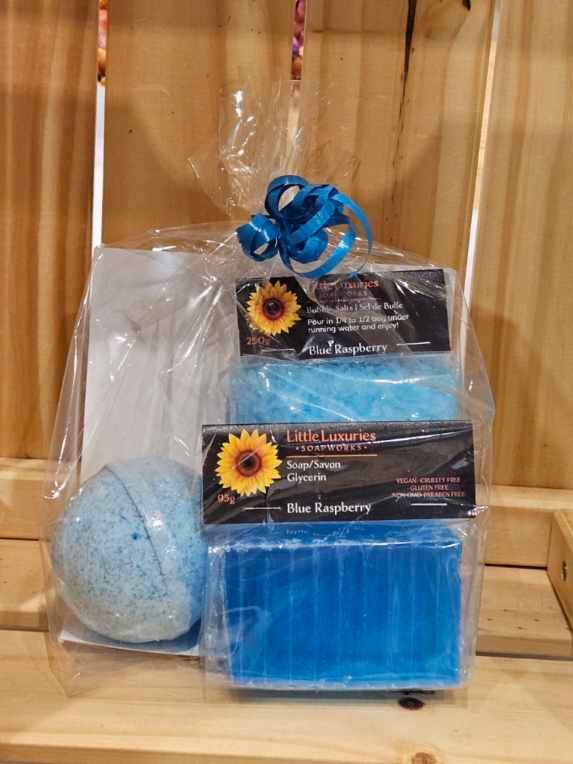 Gift pack with blue raspberry soap, bath bomb, and bubble salts in clear packaging and blue ribbon.