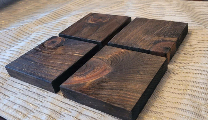 Set of four handcrafted rustic wood coasters on table.