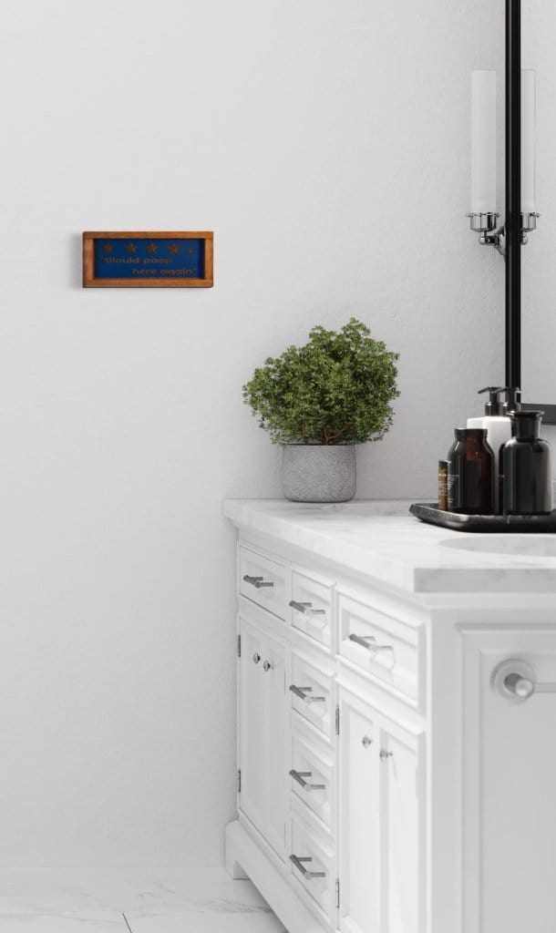 Rustic 'Would Poop Here Again' bathroom sign in modern bathroom setting.