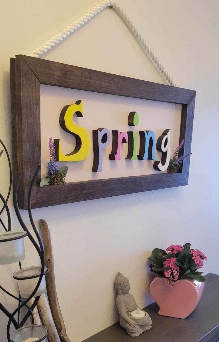 Handmade wooden sign with colorful spring letters, featuring rope attachment for easy hanging.