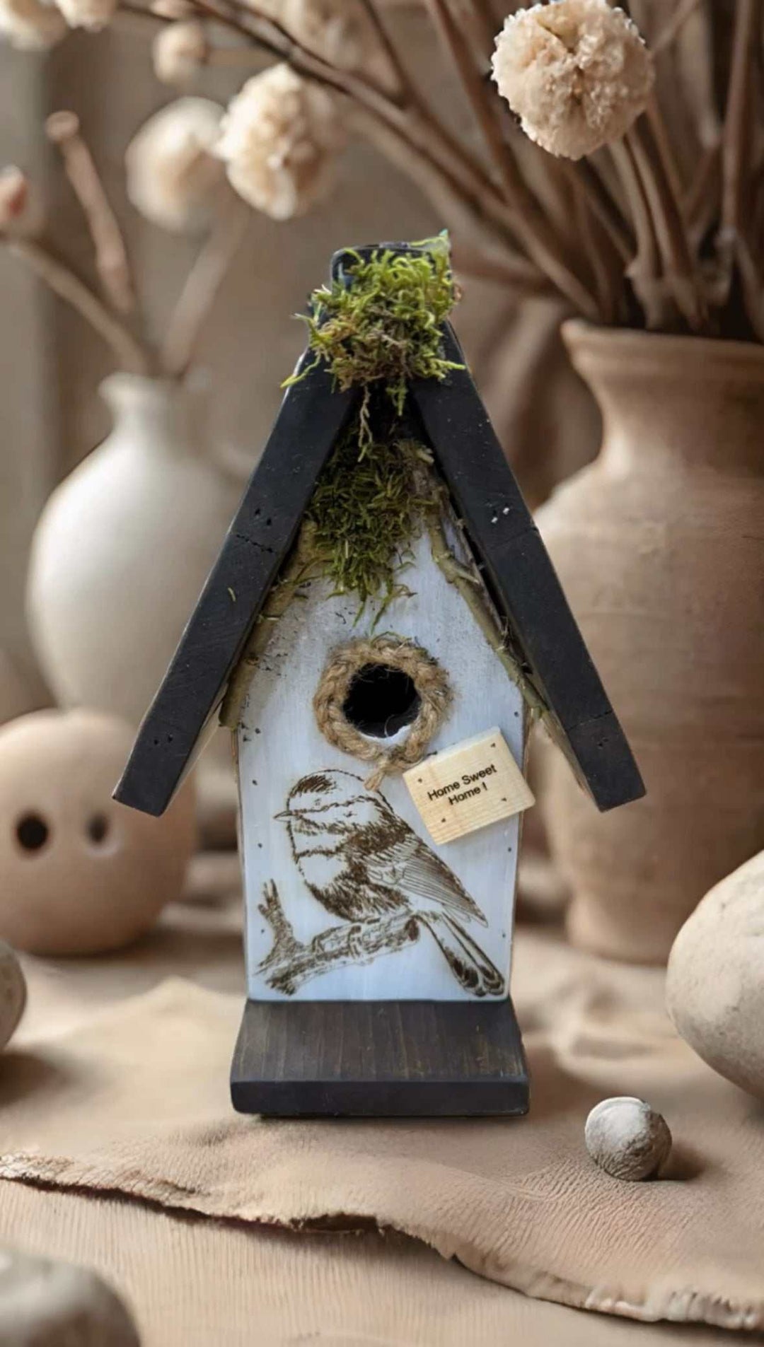 Handcrafted pine birdhouse with moss and engraved bird design, ideal for gardens.