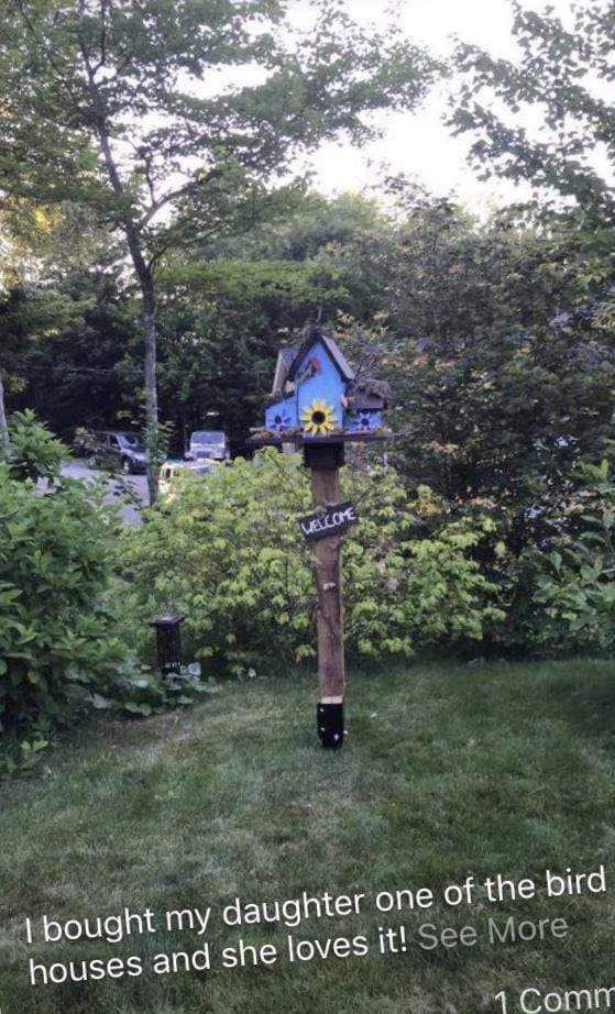 Triple blue wooden birdhouse on pole with welcome sign in garden setting