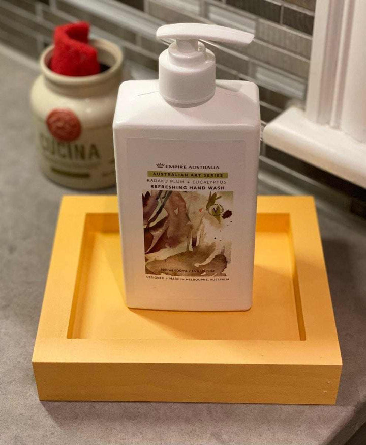 Handcrafted yellow pine soap dish holding a pump bottle on a bathroom counter.