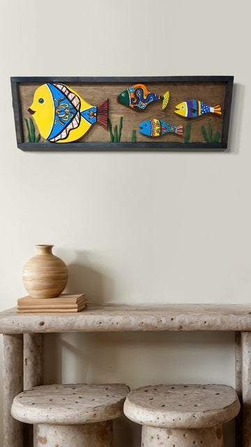 Handmade framed folk art wall decor featuring colorful hand-painted fish, perfect for coastal or cottage-style interiors.
