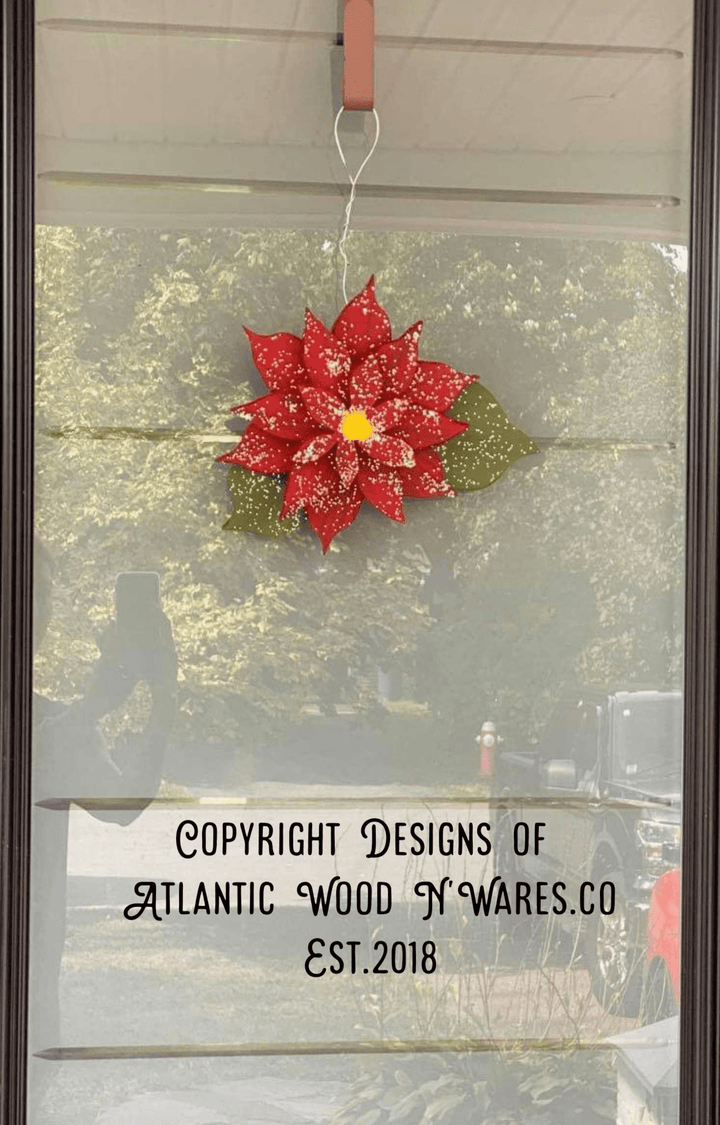 Wooden poinsettia decoration hanging on a glass door.