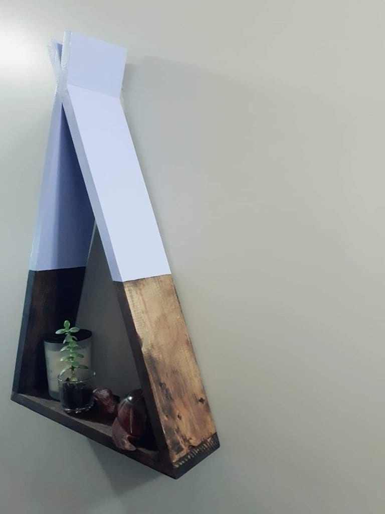 Handcrafted teepee-shaped wooden shelf on wall with decorative items.