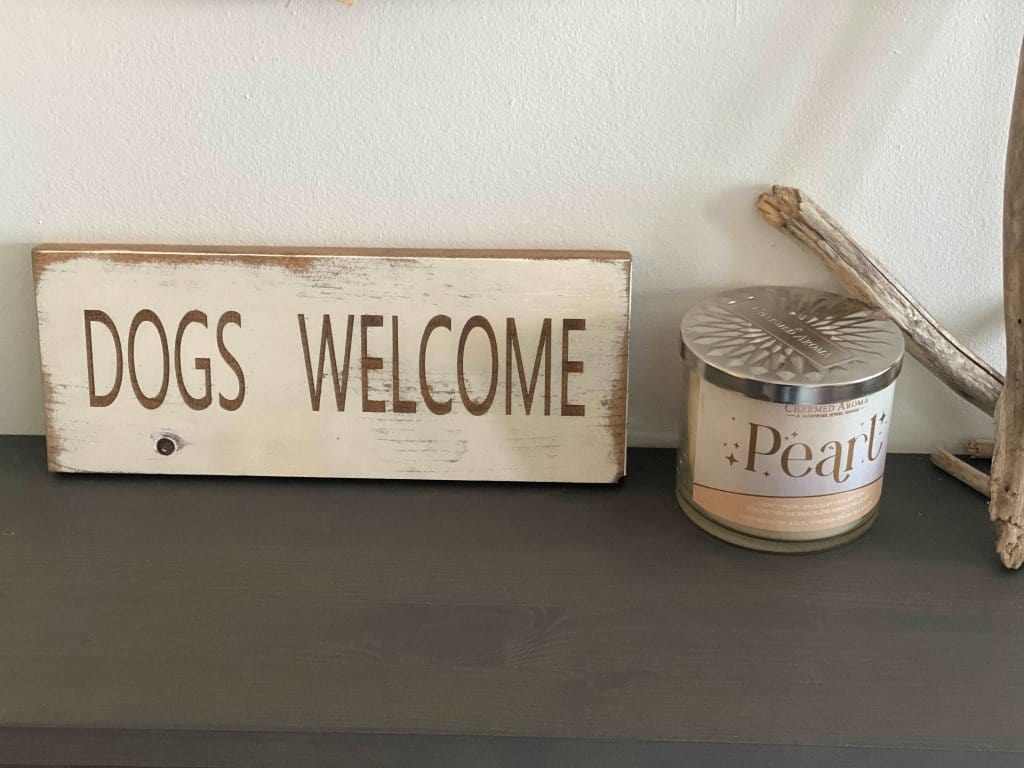 Laser-engraved "Dogs Welcome" sign with antique white paint on wooden board, perfect for home decor.