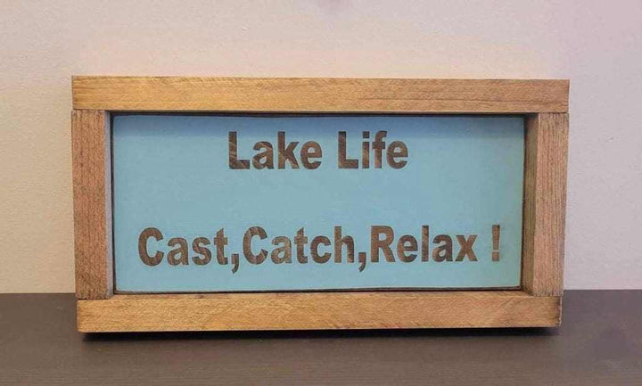 Laser engraved wood sign with "Lake Life, Cast, Catch, Relax!" text, perfect for outdoor enthusiasts.