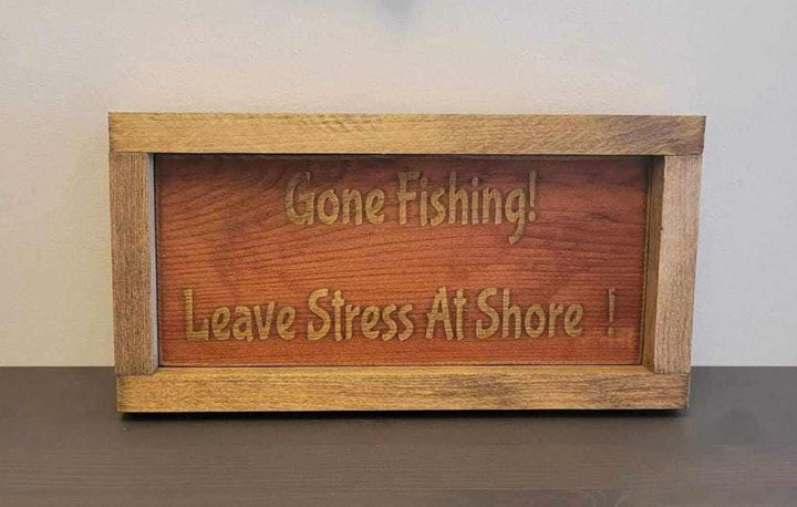 Laser engraved wood sign with "Gone Fishing! Leave Stress At Shore!" message, perfect for outdoor enthusiasts.