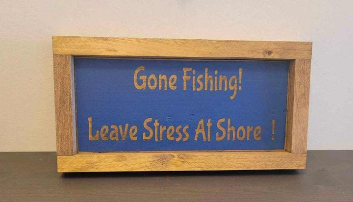 Laser engraved wood sign with "Gone Fishing! Leave Stress At Shore" message, ideal for outdoor enthusiasts and rustic decor.