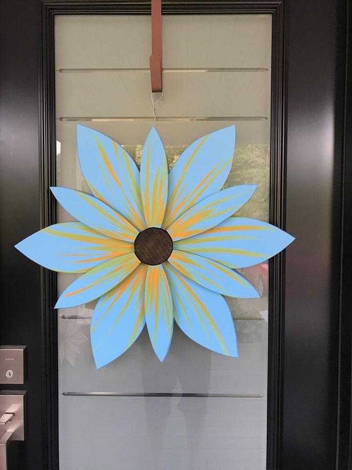 Handcrafted 22-inch pine wood flower with vibrant oceanic design hanging on a door.