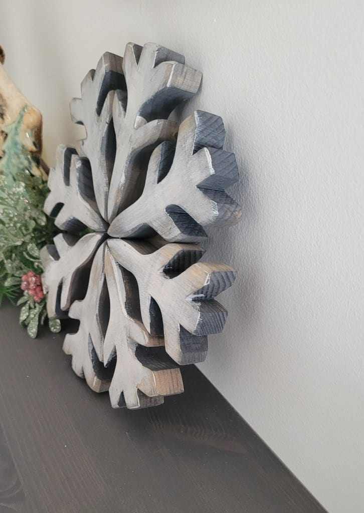 Handmade wooden snowflake decoration with rustic appeal and galvanized wire hanger.