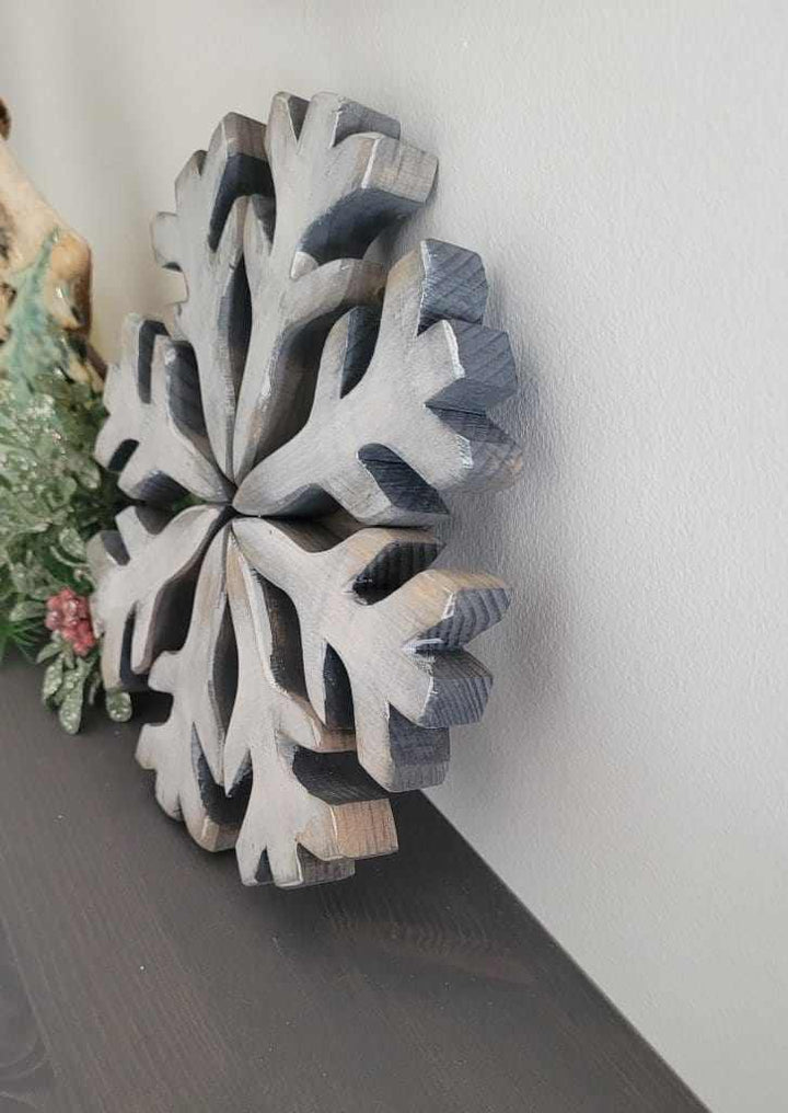 Handmade wooden snowflake decoration with rustic appeal and galvanized wire hanger.