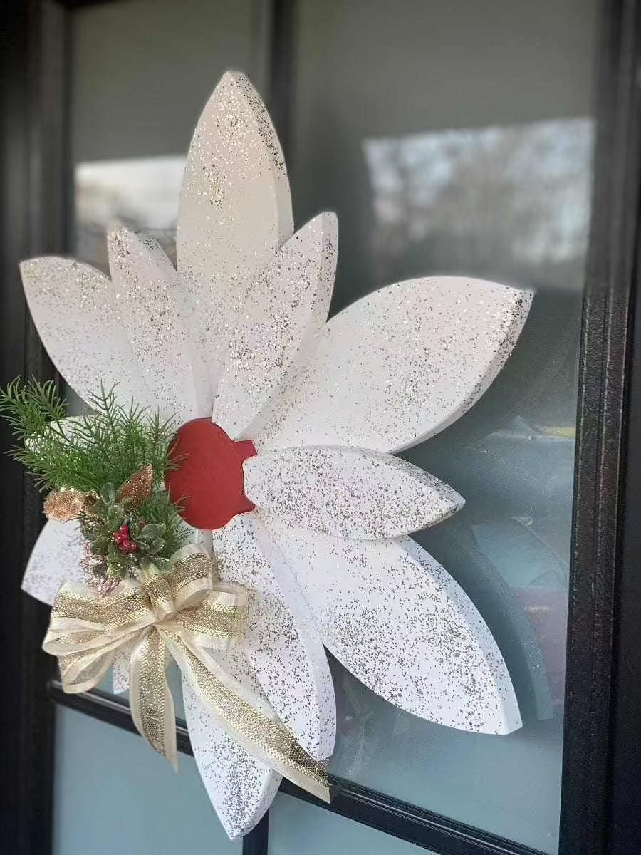 Christmas wooden flower door decoration with white petals, red center, glitter accents, and festive greenery with a gold bow.