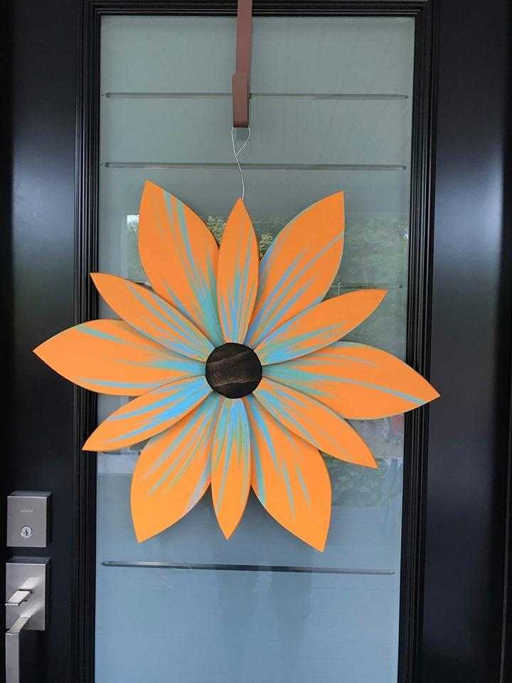 Handcrafted Nova Scotia wood flower art decor on a door with vibrant orange and blue petals.