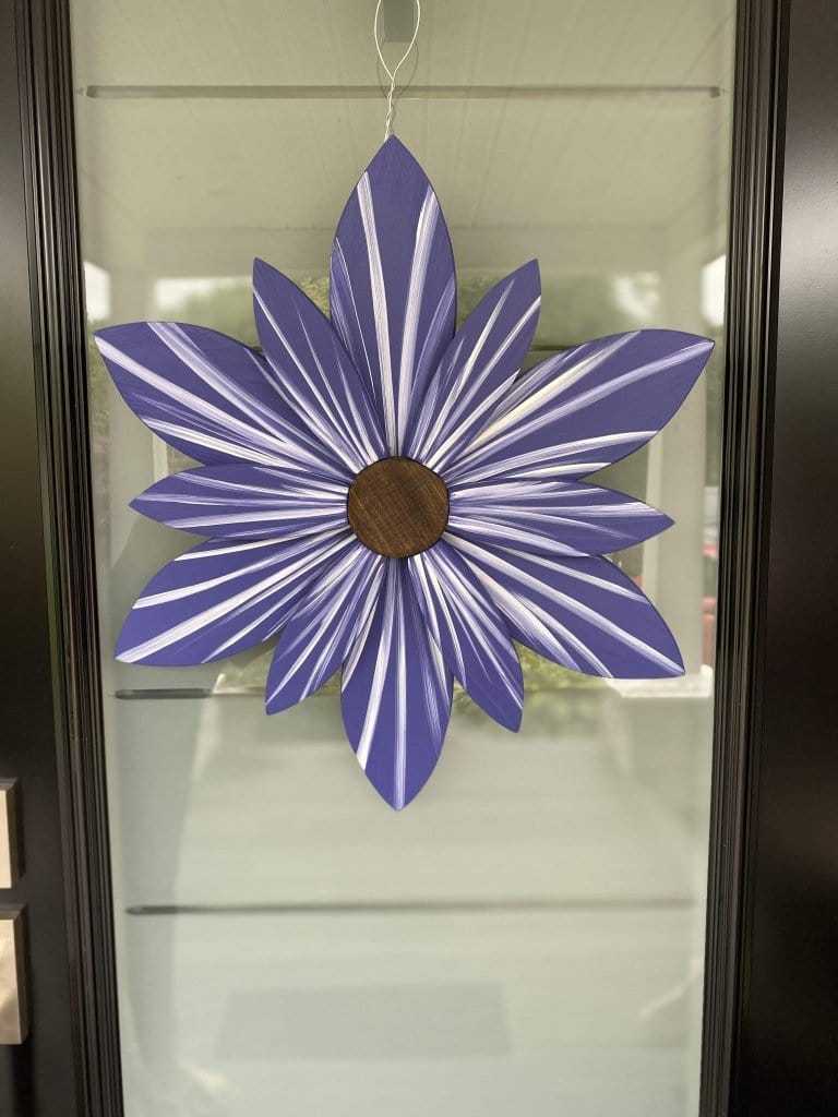 Scandinavian blue wooden flower art with white accents, handcrafted and painted, hanging on a wire hanger.