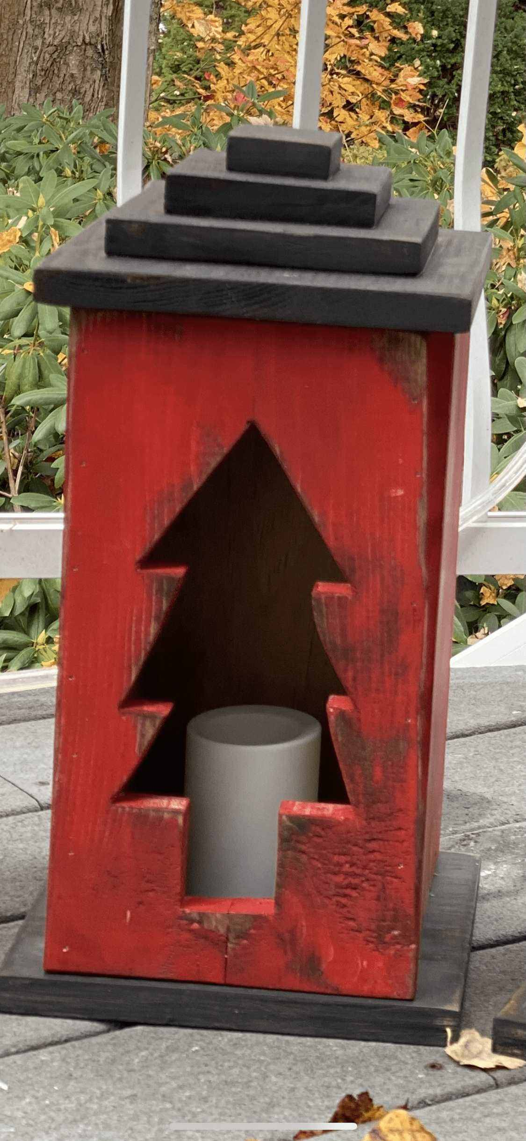 Handcrafted red wooden lantern with tree cut-out design for cozy ambiance.
