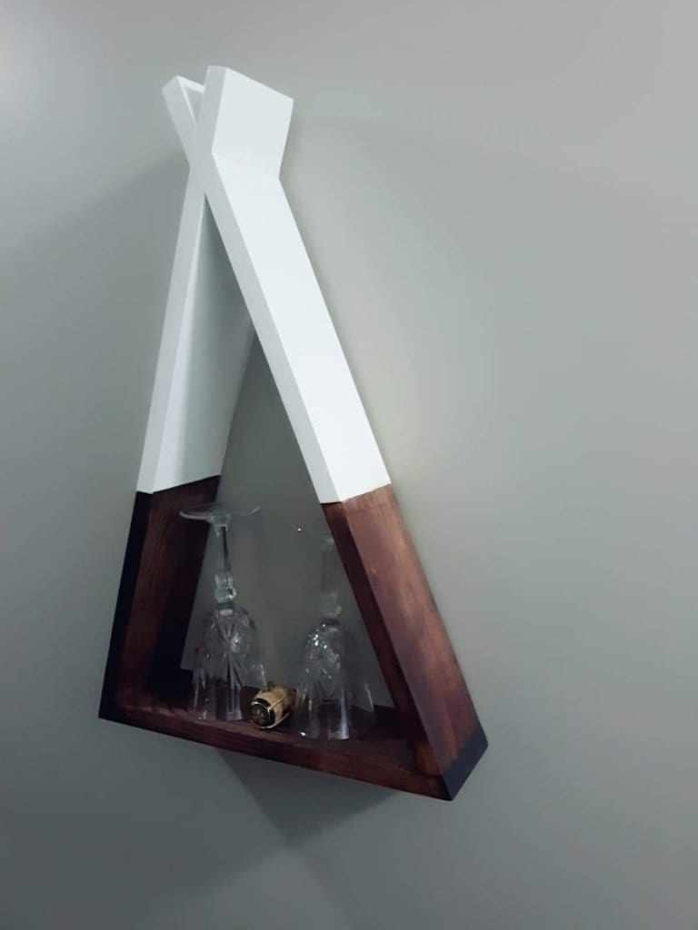 Handcrafted wooden teepee shelf mounted on wall displaying items.