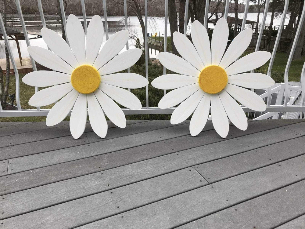 Hand-painted wooden art daisies on a deck overlooking a lake, symbolizing new beginnings and motherhood.