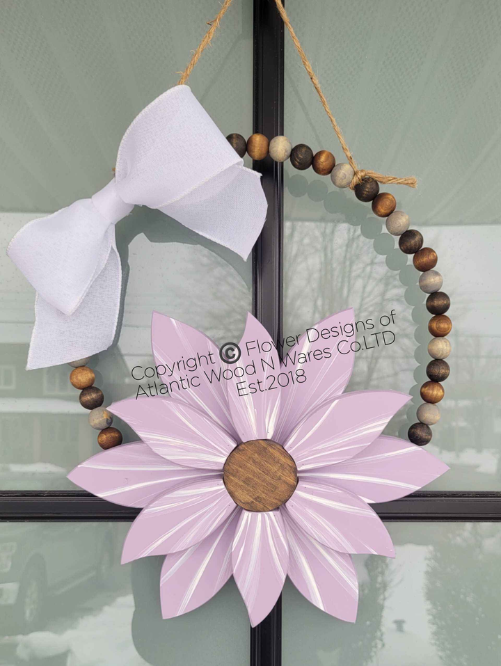 Boho style wooden bead wreath with a painted wood flower and white bow, featuring hand-stained beads.