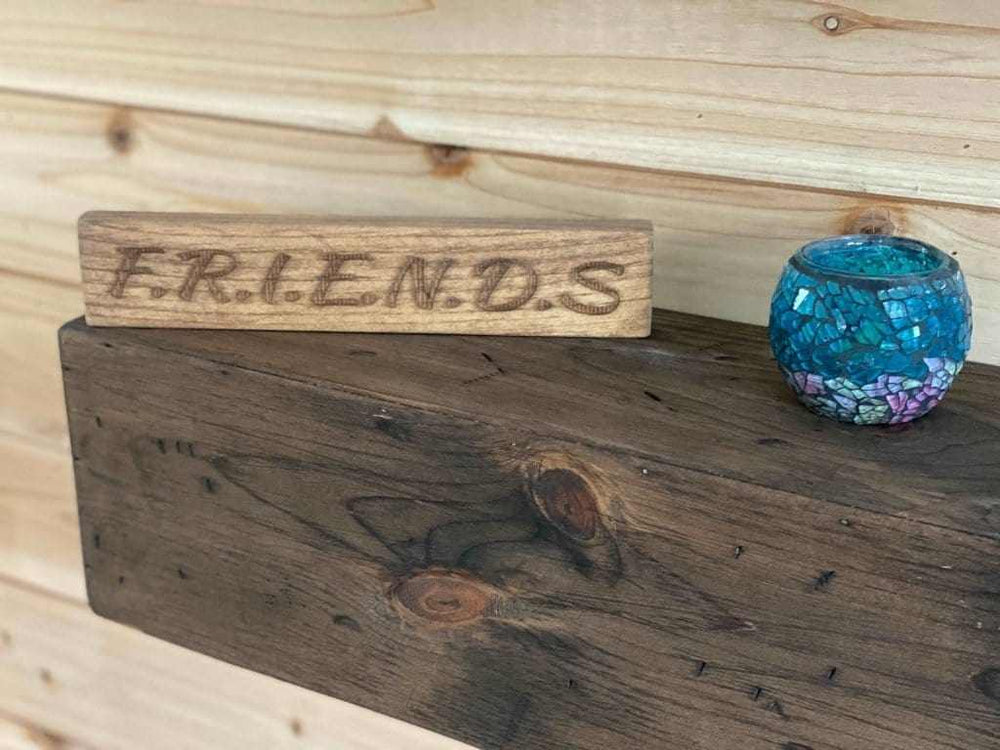 Laser engraved wooden friendship sign on shelf.