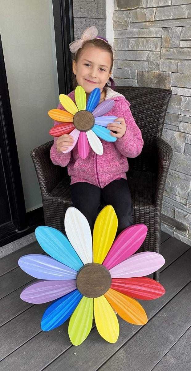 Young girl holding colorful wooden flower art for Sofia Daisy Campaign supporting children with congenital heart conditions in Canada