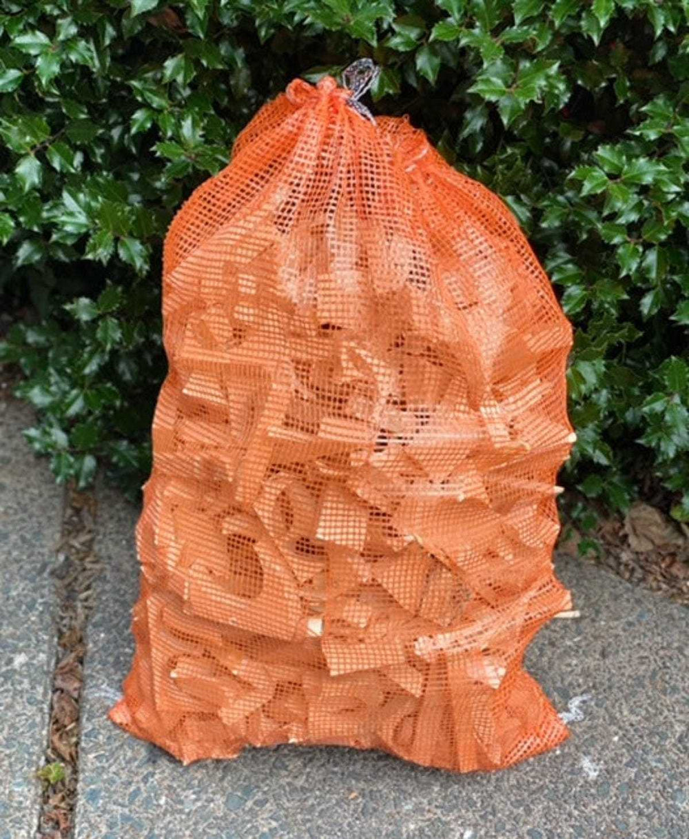 Pine wood kindling in large orange mesh bag for fireplace, campfire, and stove use.