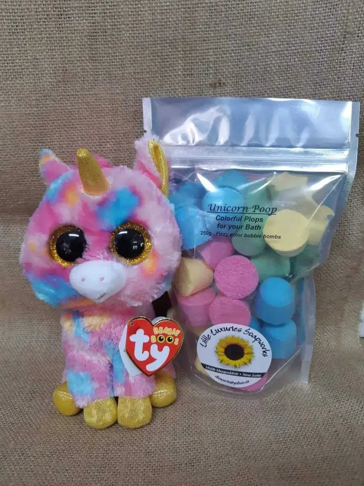 Colorful unicorn plush toy beside a pouch of Unicorn Poop bath bombs with vibrant pastel colors for fun, foaming baths