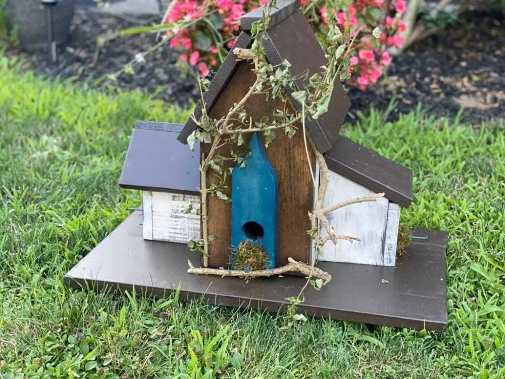 Charming triple birdhouse in pine wood with decorative foliage, set on a lawn, ideal garden addition.