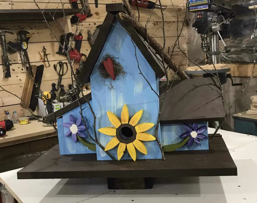 Handcrafted triple birdhouse with blue and brown paint featuring sunflower and purple flower decorations, suitable for garden use