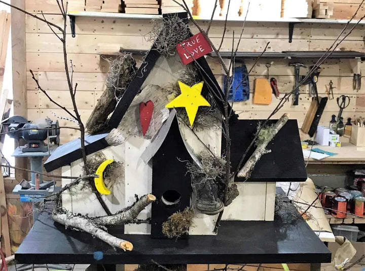 Triple wooden birdhouse with three compartments, decorated with branches, stars, and heart accents for garden decor.