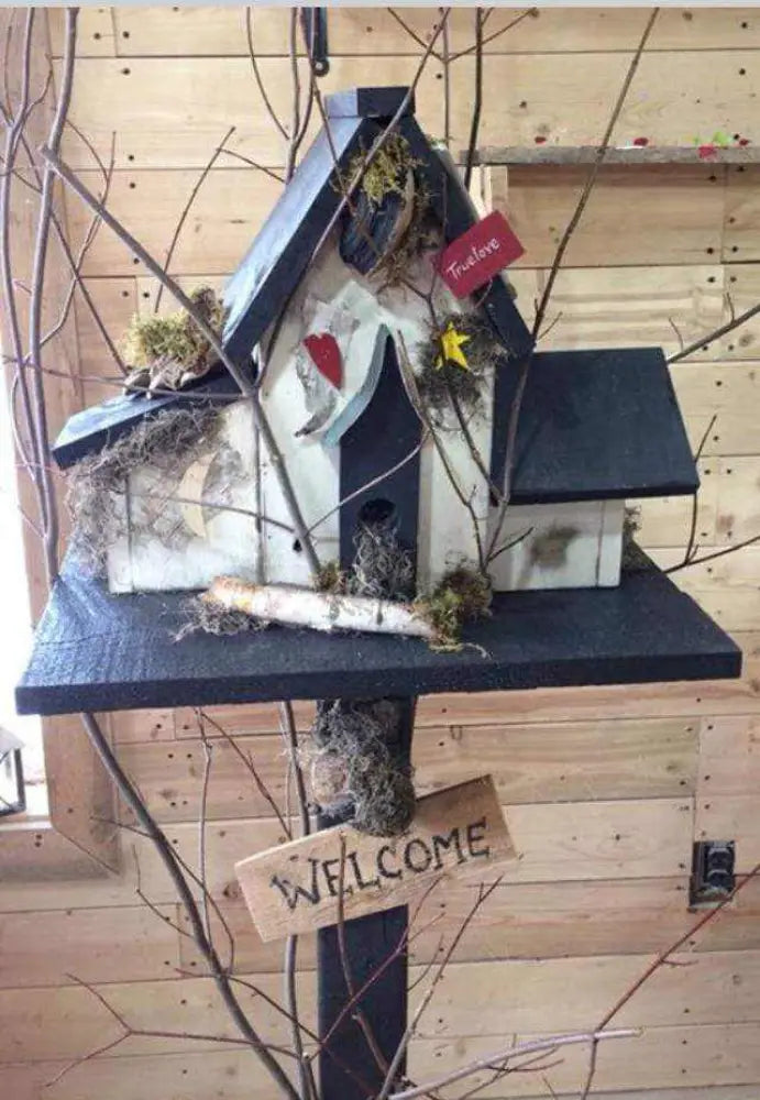 Triple birdhouse with a welcome sign, black roof, and rustic decorations, perfect for garden charm.